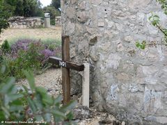 Hinter der Kapelle steht ein kleines Holzkreuz, 05/2019